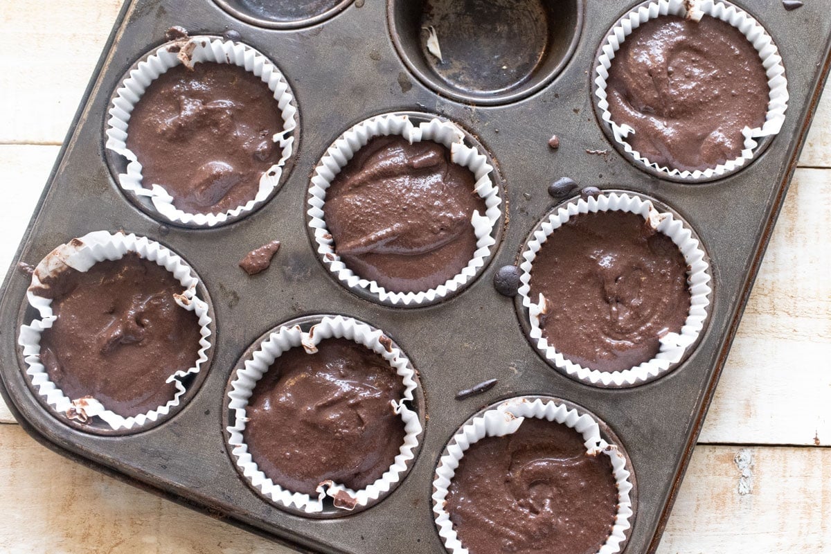 Cupcake batter in paper cups in a pan.