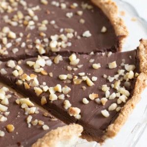 A slice of keto chocolate tart topped with hazelnuts.