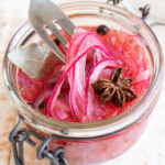 Sugar free pickled onions in a jar and a fork lifting up some of the onion slices.
