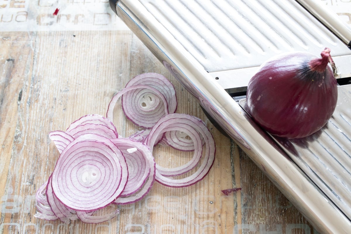 A mandoline slicer with sliced red oniom.