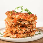 A stack of chicken fritters topped with a dollop of yogurt.