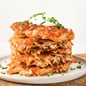 A stack of chicken fritters topped with a dollop of yogurt.