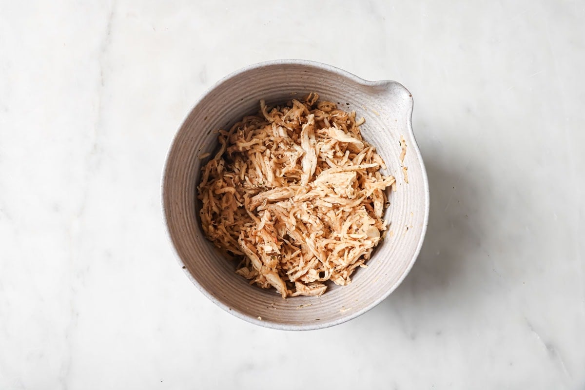 Shredded cooked chicken and spices in a bowl.