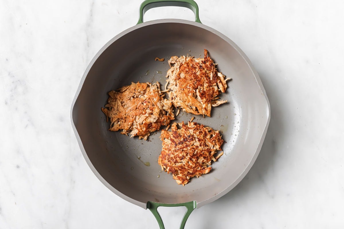 3 chicken fritters in a frying pan.