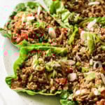 Asian pork lettuce wraps on a plate topped with spring onion.