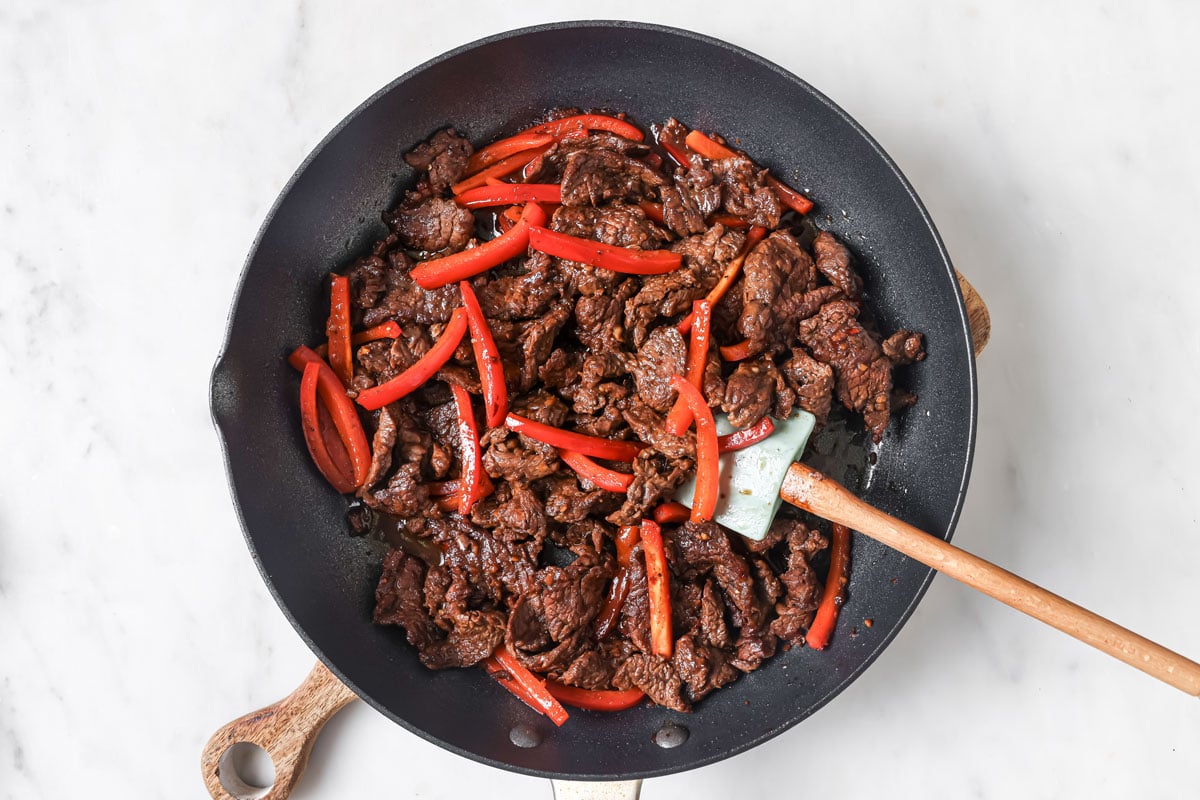 Adding the sliced red peppers to the browned beef.
