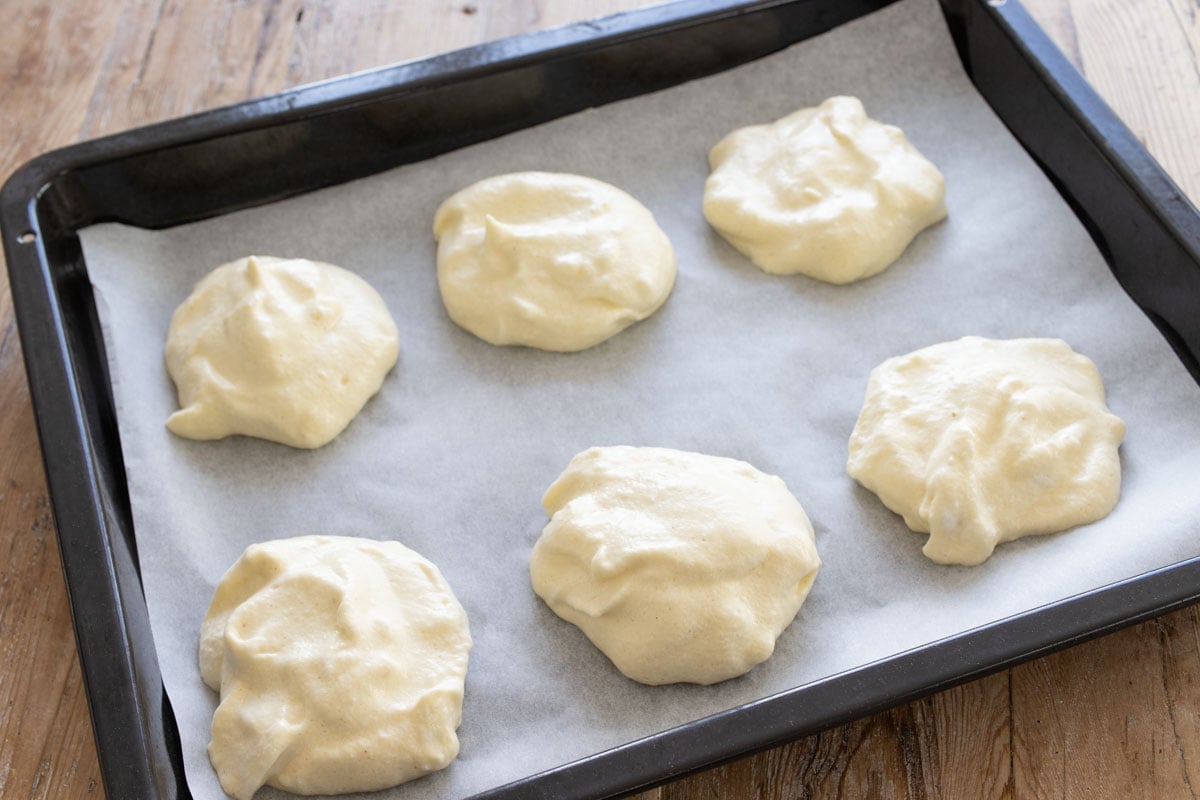Cloud bread batter dotted onto a parchment paper lined baking sheet.