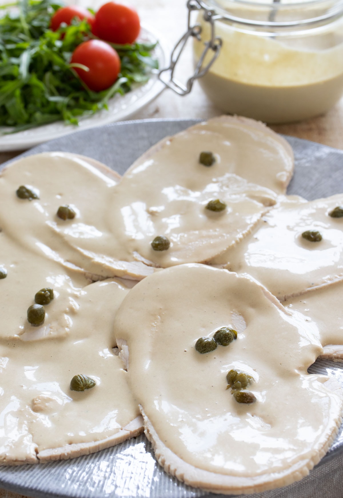 Tonnato sauce on turkey breast slices topped with capers.