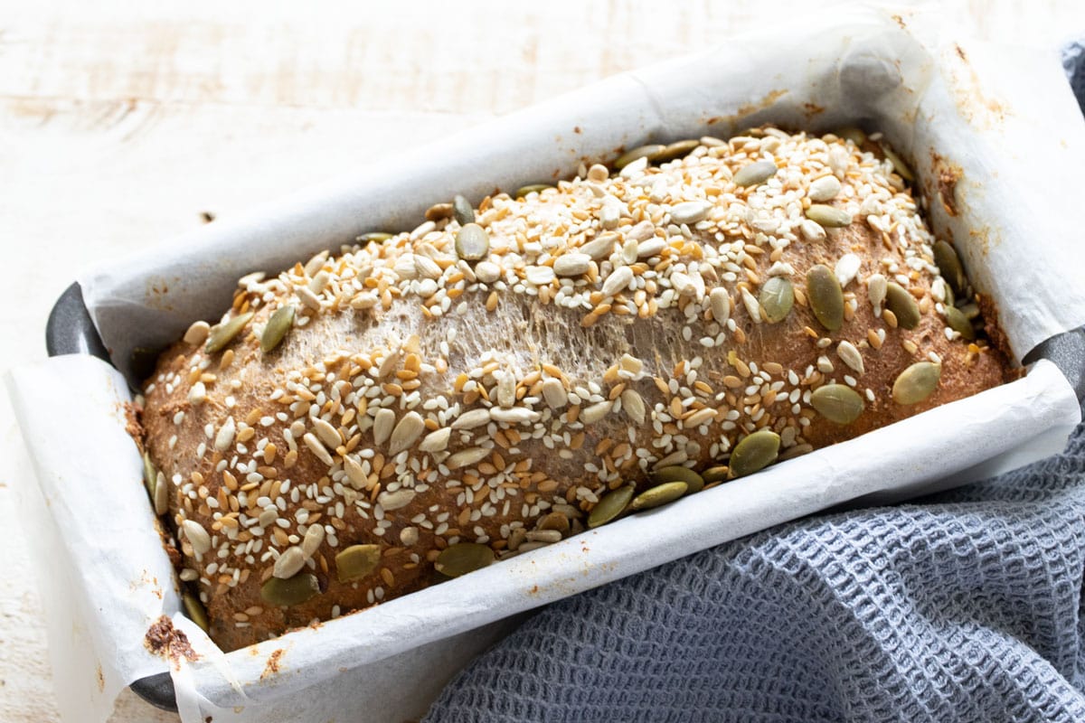 Baked cottage cheese bread topped with seeds in a lined loaf pan.