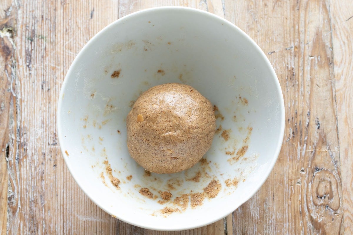 The dough shaped into a arge ball, in a bowl.