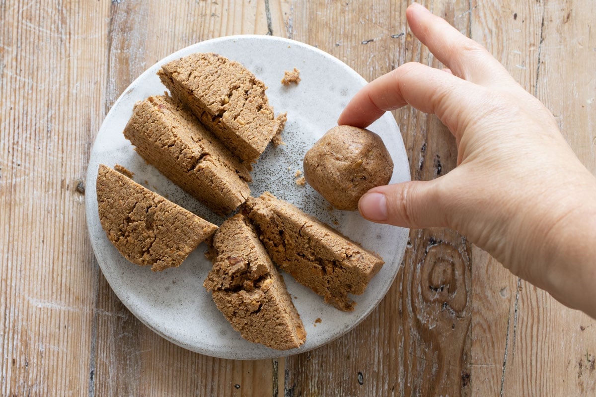 Hand holding a protein ball and portioned dough.