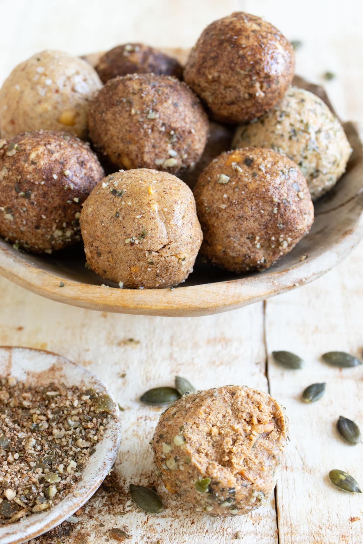 Low carb protein balls in a bowl and one ball in front of the bowl is bitten into.