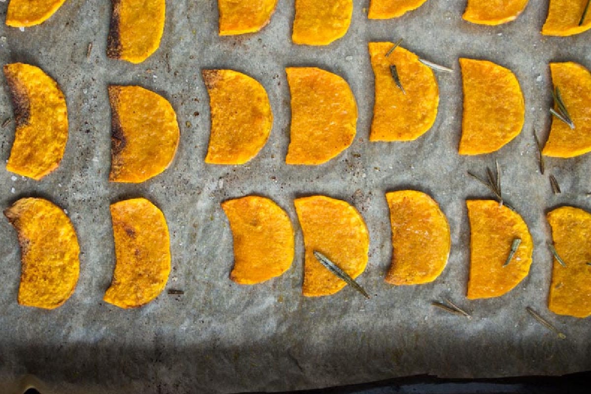 Butternut squash chips are perfect for those times when you long for crisps, but don't want to load up on carbs. Butternut squash chips on parchment paper after baking.