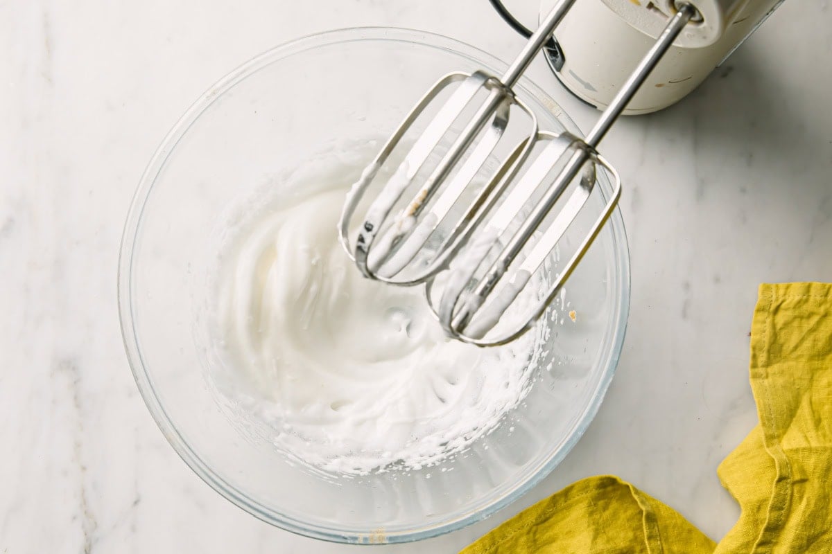 A bowl with whipped egg white and a blender.