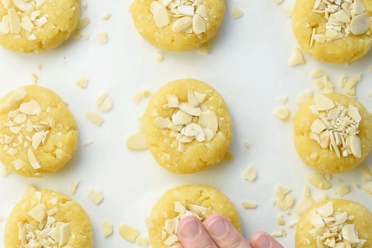Pressing the chopped almonds and coconut onto the cookies and flattening them.