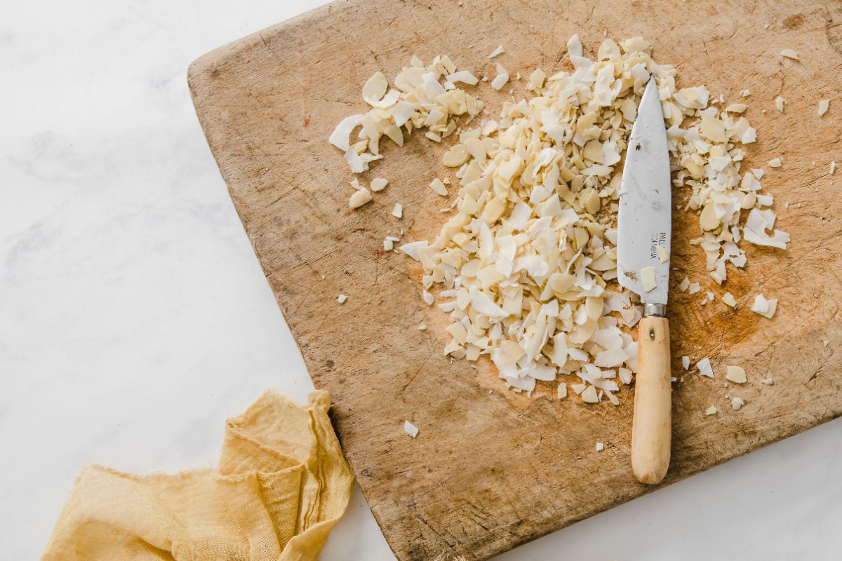 Chopping flaked almonds and coconut on a wooden board.