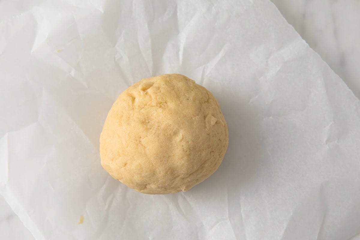 A shortcrust pastry dough ball on parchment.