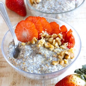 A bowl of chia porridge topped with sliced strawberries and walnuts.