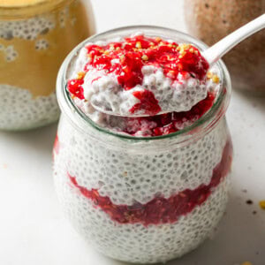 A glass jar with protein chia pudding and raspberry swirl.