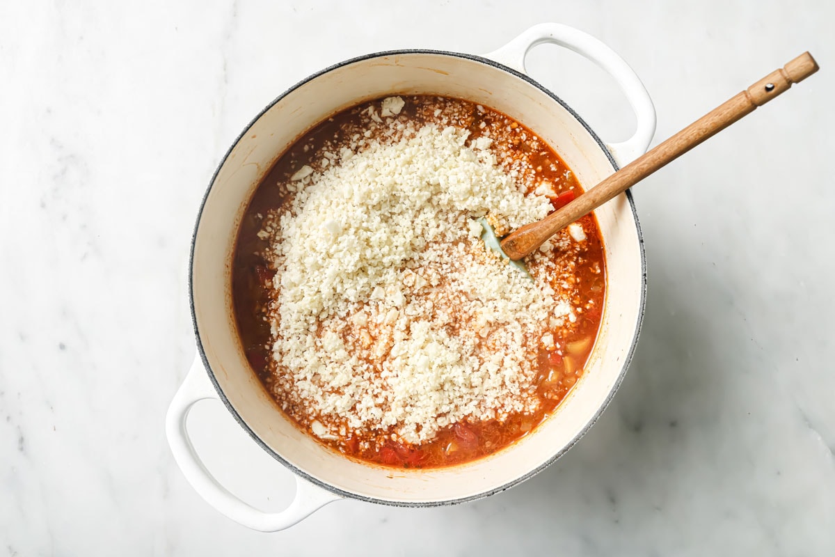 Adding cauliflower rice to the soup.