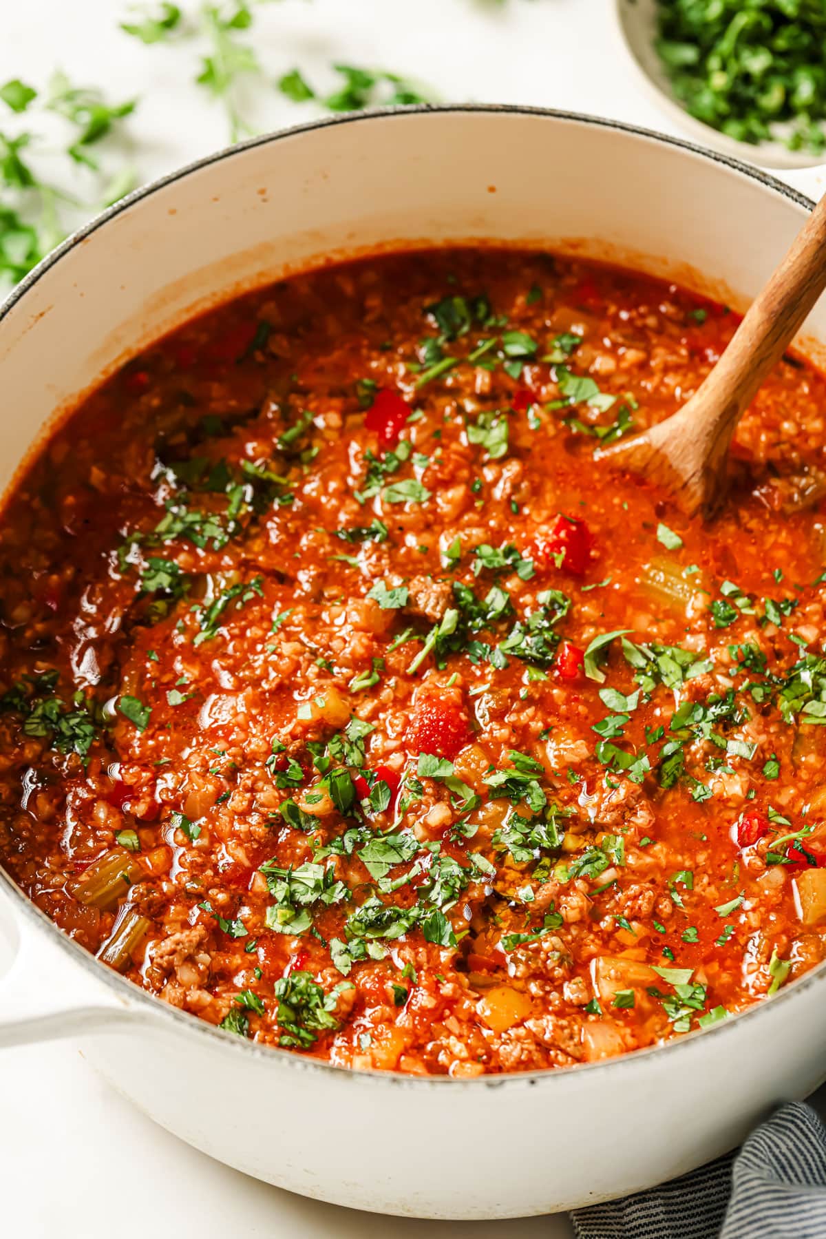 Keto stuffed pepper soup in a large pot with a wooden ladle.