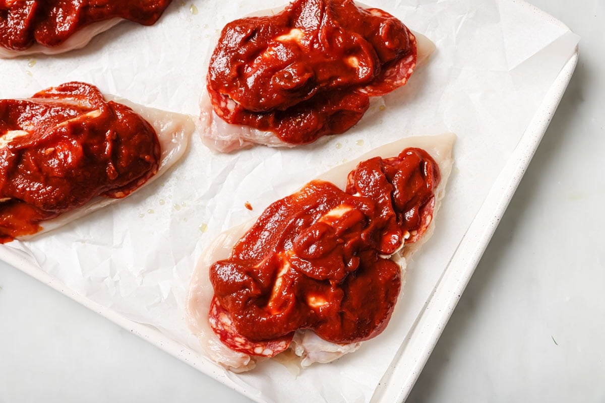 The chicken fillets spread with marinara sauce.
