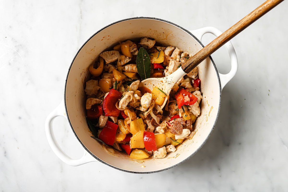 Vegetables, chicken and chopped chorizo in a pot.