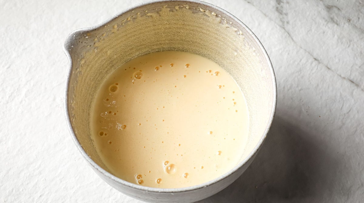 Blending egg yolks and sweetener in a bowl.