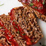 Keto meatloaf slices topped with marinara sauce and fresh parsley.