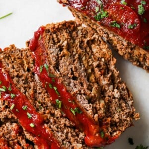 Keto meatloaf slices topped with marinara sauce and fresh parsley.