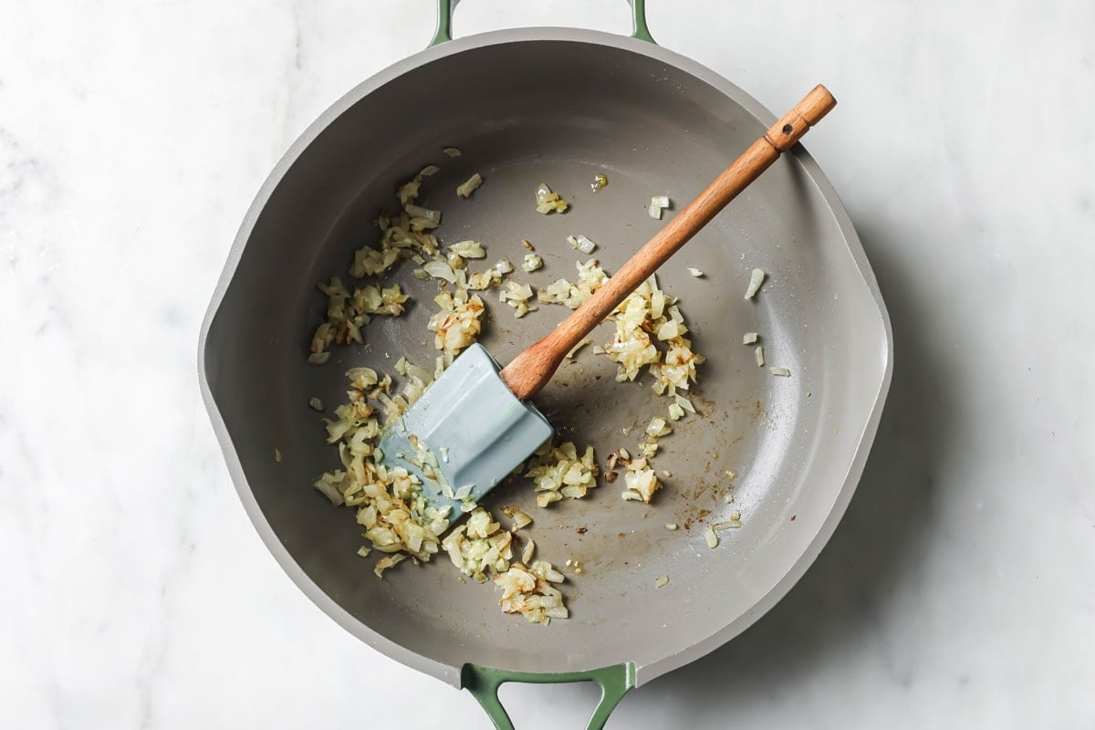 Sauteing diced onions in a pan and a spatula.