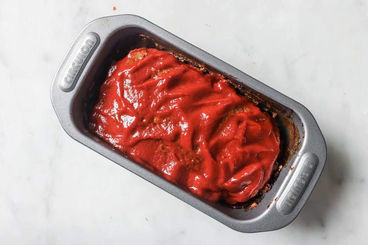 The pre-baked meatloaf in a tin spread with sugar free ketchup.