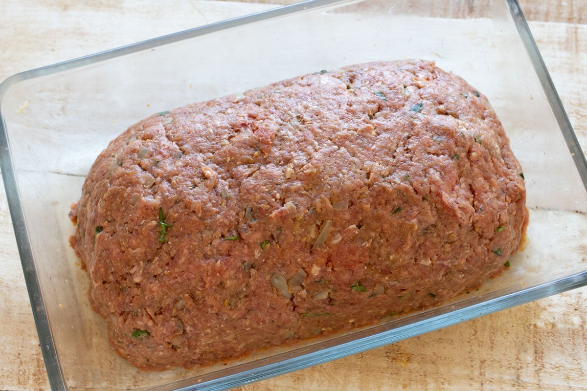 Uncooked meatloaf mixture formed in a casserole dish.