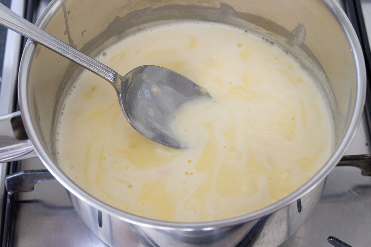 Heating cream and sweetener in a pot and a spoon.