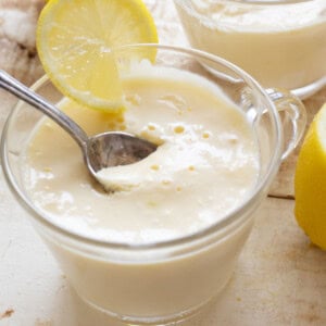 A dessert cup with keto lemon posset decorated with a lemon slice and a spoon.