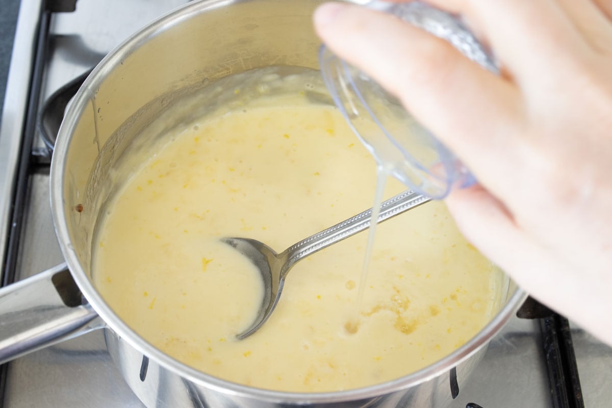 Pouring lemon juice into the heated cream mixture.
