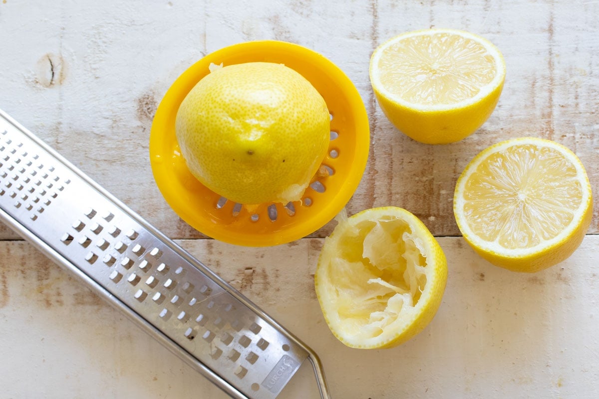 Squeezing juice out of lemon halves and a grater.