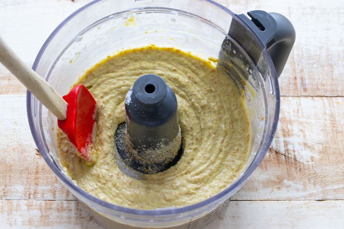 The avocado batter in the food processor bowl and a spatula.