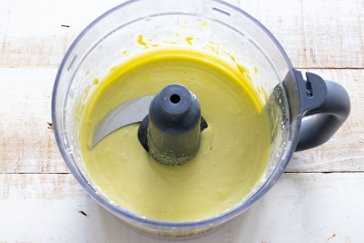 Blended avocado, eggs and yogurt in a food processor bowl.