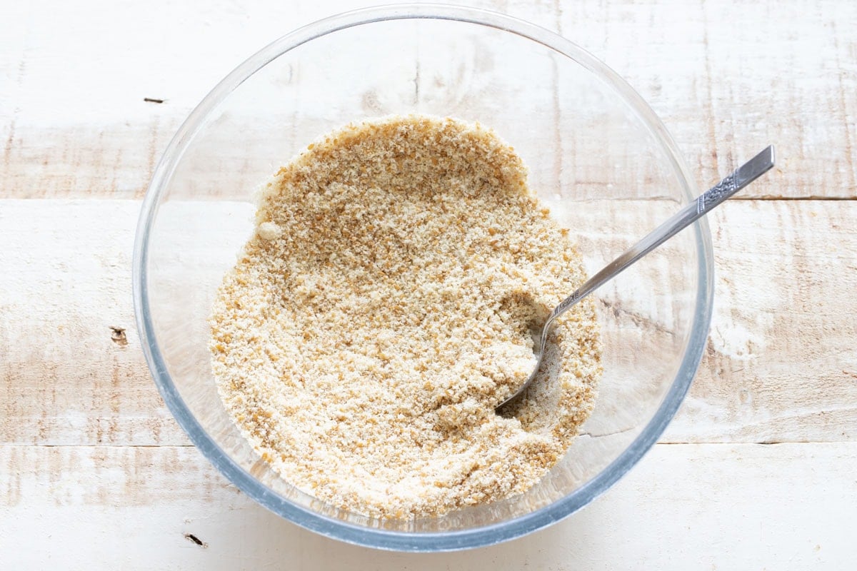 Almond flour, ground flax and other dry ingredients stirred together in a glass bowl.