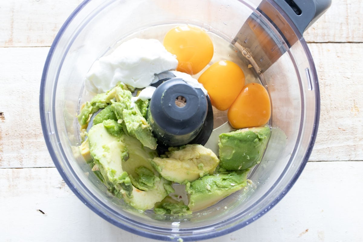 Avocado flesh, Greek yogurt and 3 eggs in a food processor bowl.