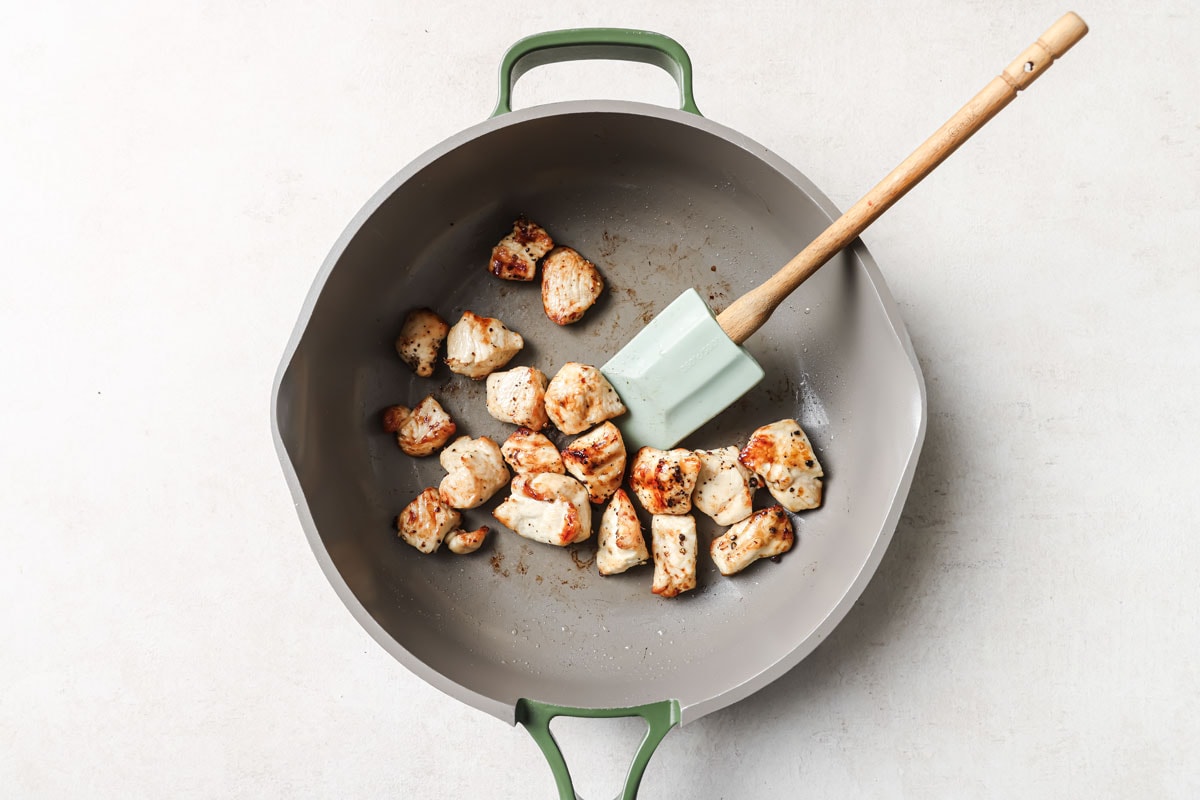Searing chicken brease cubes in a frying pan.