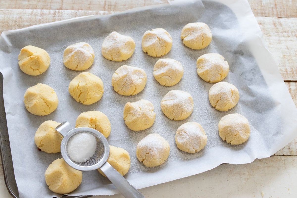Dusting cottage cheese cookies with powdered sweetener in a sieve.