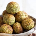 keto pistachio cookies stacked in a wooden bowl.
