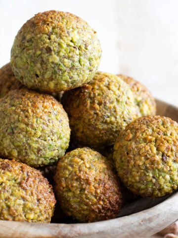 keto pistachio cookies stacked in a wooden bowl.