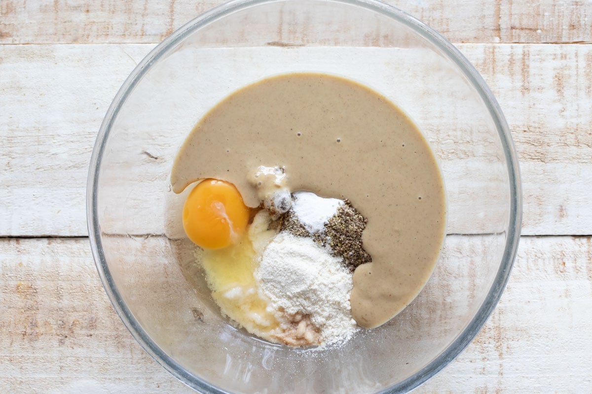 Tahini, egg and all other ingredients to make tahini cookies in a glass bowl.