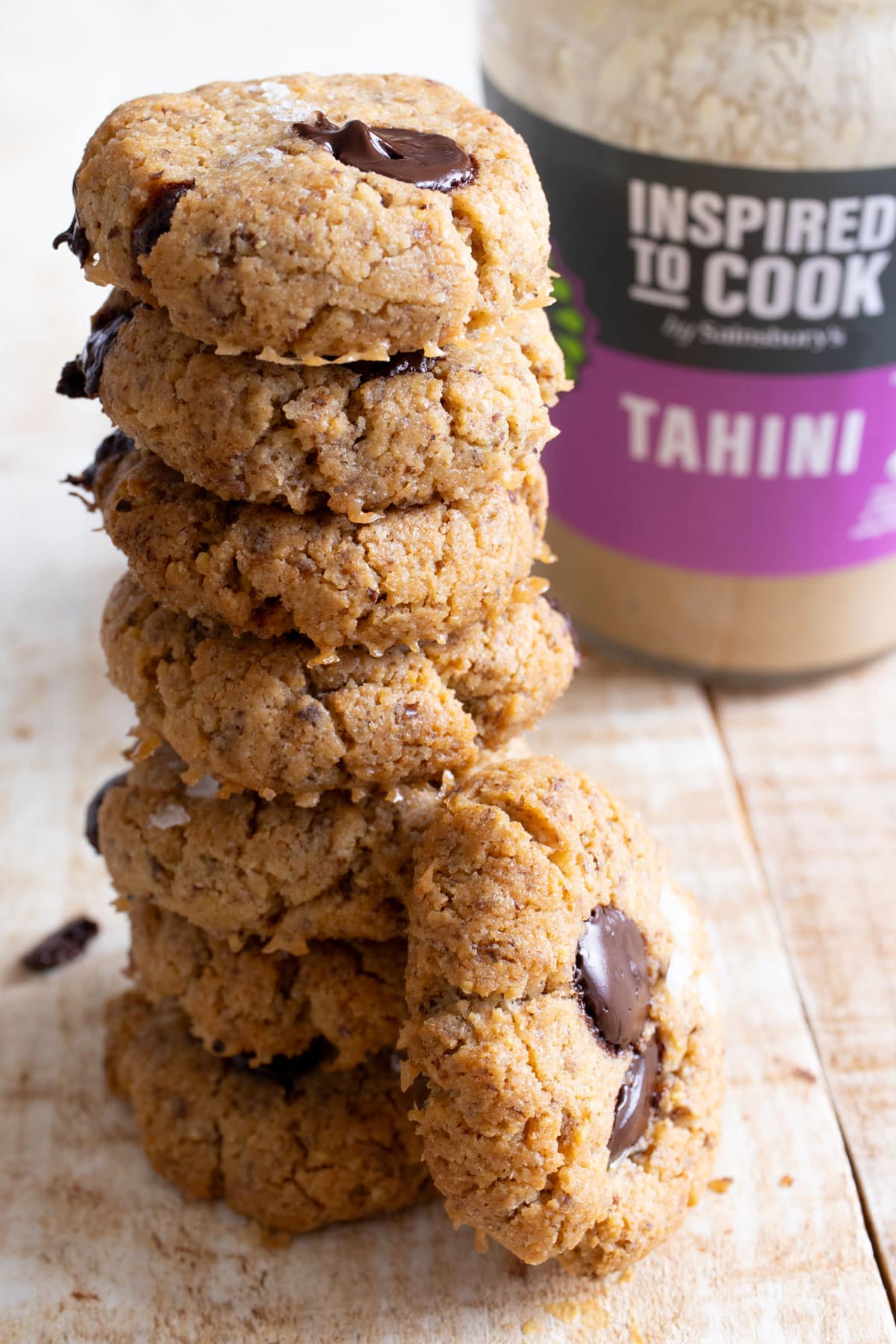 A stack of keto tahini cookies with a jar of tahini in the background.