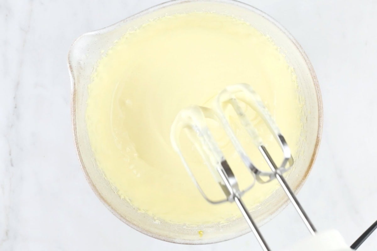 Beating egg yolks and sweetener with an electric mixer.