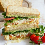 Keto sandwich sliced open filled with avocado, lettuce, tomato and cheese.