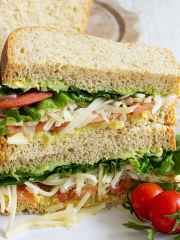 Keto sandwich sliced open filled with avocado, lettuce, tomato and cheese.
